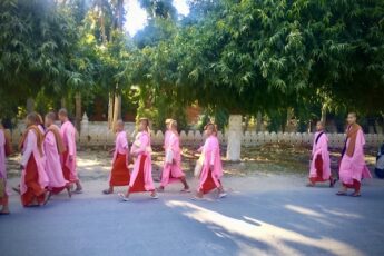 vaaleanpuna-puna asuisia lapsimunkkeja kavelee Mandalayn kadulla