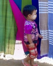 pikkuinen iloisesti pukeutunut lapsi kavelee torilla myanmarissa