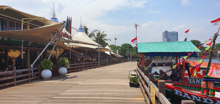 Jakartan rannalla oleva ravintola  ja laiturilla paikallinen turistivene.