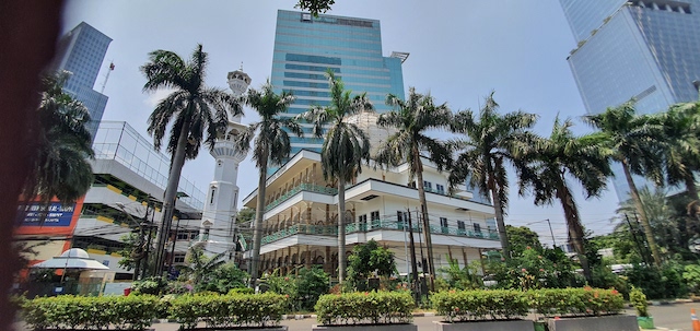 iso valkoinen moskeija Jakartassa, jonka edustalla on palmupuita.