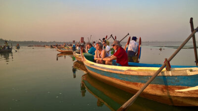 turisteja istumassa ja katsomassa auringonlaskua turistiveneissa.