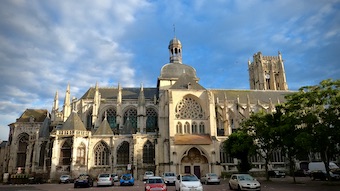 Saint Jacques kirkko sinisen taivaan alla ja kirkon edustalla on autoja parkissa.