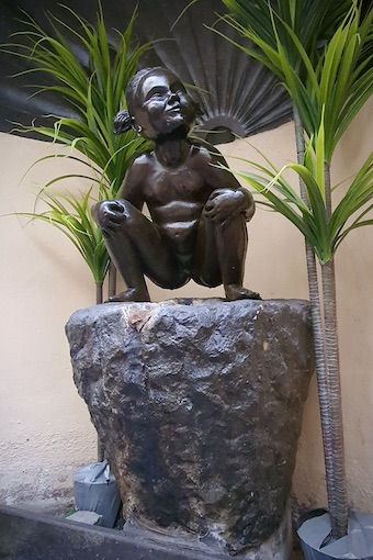 Janneken Pis -patsas istuu kiven laella. 