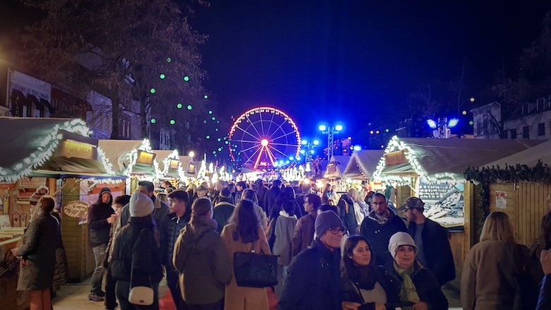 Brysselin joulumarkkinoilla olevia valaistuja kojuja ja taustalla korkea maailmanpyora.