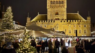 Bruggen joulumarkkinoilla olevia kojuja valoineen ja taustalla Bruggen kellotapuli.
