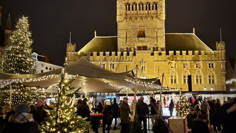 Bruggen joulumarkkinoilla olevia kojuja valoineen ja taustalla Bruggen kellotapuli.