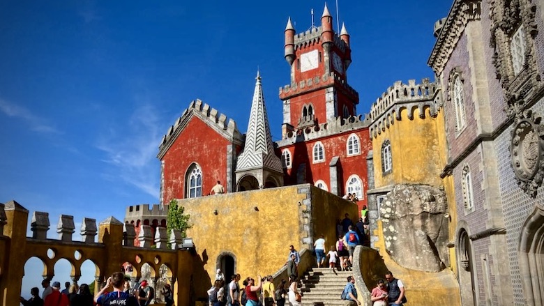 Ulkoasultaan punakeltainen Penan palatsi ja turisteja astelee rappuja pitkin palatsiin.