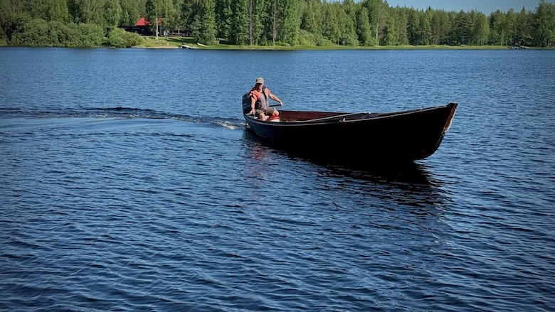 Puuvene ja pelastusliivinen mies.