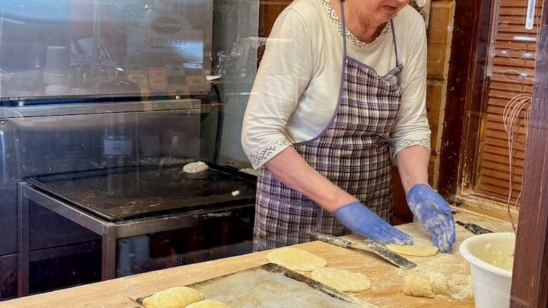 Nainen leipoo piirakoita, karjalaisia vatruskoita.