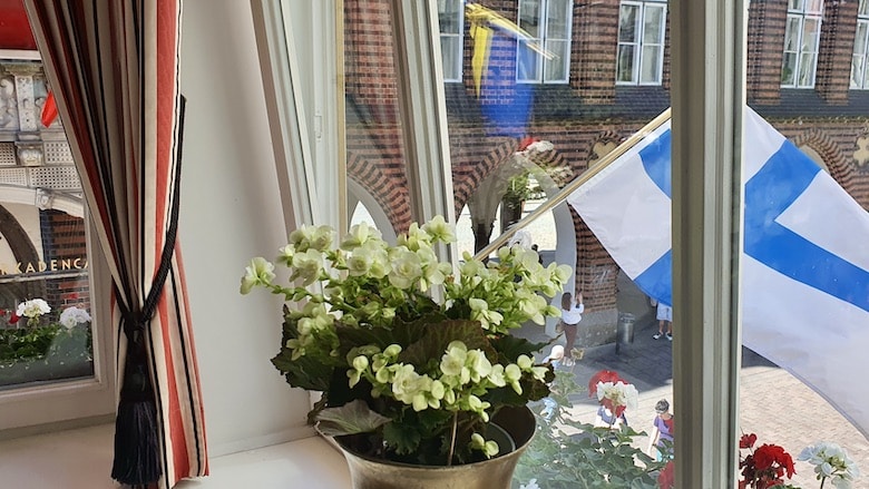 Suomen lippu liehuu ikkunan takana.